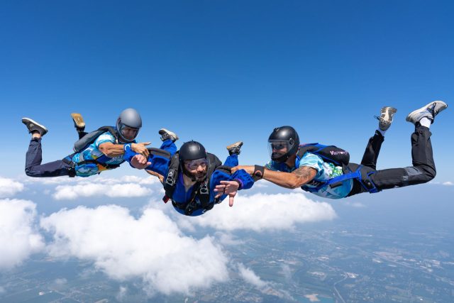 AFF student with two instructors with a small wisp of cloud in the background