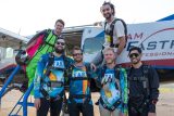 Group of male skydivers pose before boarding the plane for a jump.